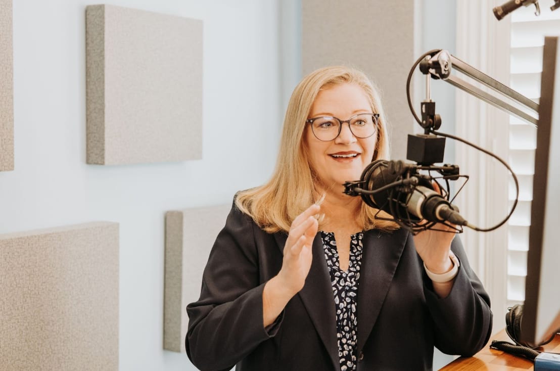 Woman with blond hair speaks into microphone