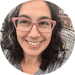 Headshot of a smiling woman with pink rimmed glasses
