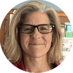 Circle crop of a headshot of a woman wearing black rimmed glasses
