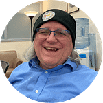 Smiling man wears black beanie with white patch