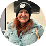 Smiling red haired woman wearing a black cap