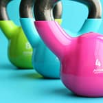 green blue and pink kettle bells on blue surface