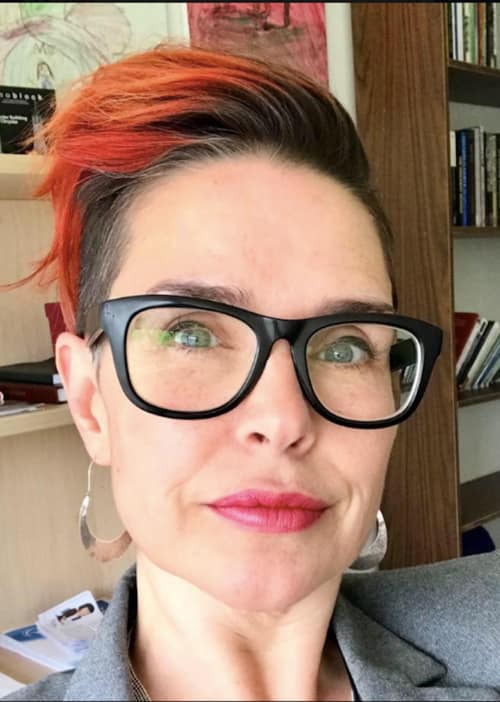Woman with short hair and black rimmed glasses wearing sliver earrings