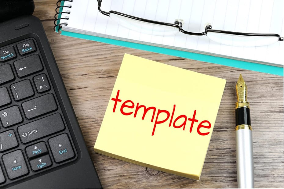 A sticky note with the word “template” written in red sits on a wooden desk alongside a laptop keyboard, a fountain pen, a pair of glasses, and a notebook—suggesting planning or instructional design work.