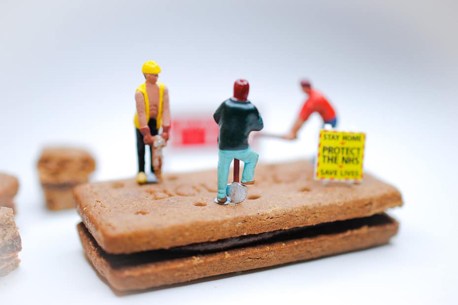 Tiny toy workmen shovel and jackhammer on a cookie